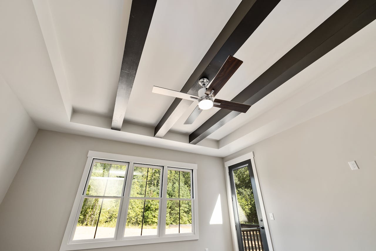 Contemporary room featuring a ceiling fan, exposed beams, and large windows.